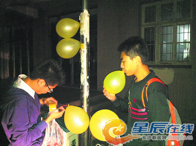 “气球哥”（左）在同学的帮助下，深夜挂气球。