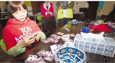  甘昌艳用家里闲置的废旧扑克牌制作各式储物盒。 记者 范远志 摄