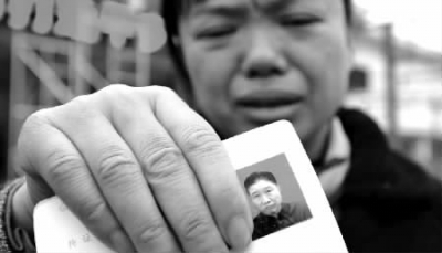  12月17日上午，长沙火车站广场，肖女士拿着开出租车老公刘义芳的照片和寻人启事寻找失去音讯的丈夫。 记者 童迪 摄