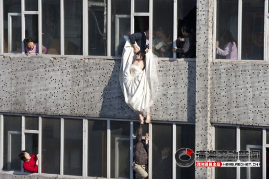 热点新闻类单幅三等奖：《跳楼新娘》。2011年5月16日，人们在吉林长春一栋居民楼解救一名身着婚纱意欲跳楼轻生的女子。图/李杨