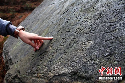 一媒体记者正在观看1号古苗文石刻上的文字。唐小晴 摄