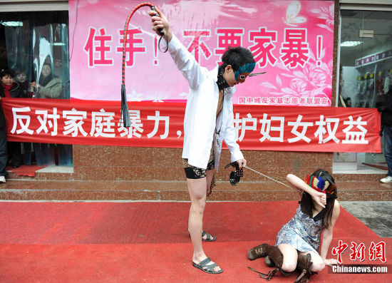 3月7日，一位女士跪倒在地，一位男士手持皮鞭，装扮成“家暴场面”出现在长沙街头。这是一场由长沙国中城市场在妇女节前夕组织开展的反对针对妇女暴力的行为艺术活动，以倡导广大市民反对家庭暴力，保护妇女权益。中新社发 杨华峰 摄