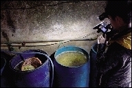 粟塘村一作坊内，水桶里泡满了未加工的黄豆，其中有发黑的豆子和各种杂物。