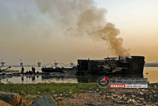 3月25日下午6时许，长沙市民朱先生路过湘江东岸猴子石大桥以南约1公里处，发现一只破旧的钢船倾斜于江面，还有烟冒出。图/朱先生 提供