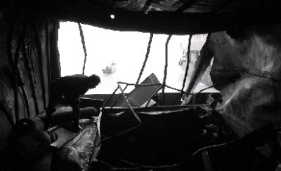  5月3日，运砂船舱被烧到只剩骨架，一位渔民探头查看被毁的船舱。图/记者辜鹏博 