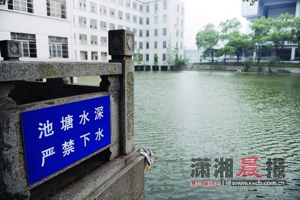 6月15日，中南林业科技大学逸夫楼前的湘林湖，湖边贴着“池塘水深，严禁下水”的提醒。图/记者张轶 