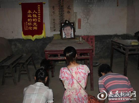 7月10日晚，3名获救者赶往邓锦杰的家中祭奠，图为获救者跪拜在邓锦杰遗像前。