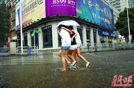 　不一会儿，暴雨突降，3名过马路的女孩共着一把伞，伞根本就盖不住三人，旁边的两个想不湿都难啊。实习生 唐俊 摄
