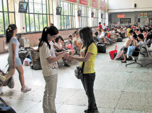 　　在长沙火车站候车室内，穿黄色T恤的90后女孩(右)拦住一位市民，出示所谓的“证明”，向她讨要“捐款”。 徐伟佳 李卓 摄影报道