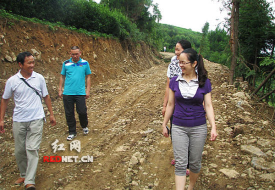 (桑植县西莲乡党委书记吴俞萍查看一条村公路整修情况。)