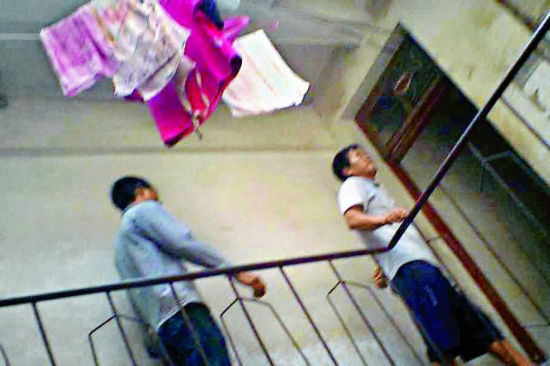 图为两名男子在楼上寻找“猎物”。天井中间挂着小姐们的衣物。