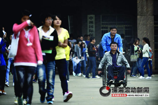 (10月16日，保险职业学院，毕明哲推着坐轮椅的王理走在校园中。图/潇湘晨报滚动新闻记者 陈勇)