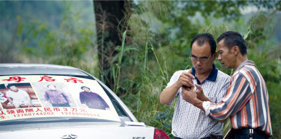 10月20日，桂林市雁山区朝阳乡，老大文辉(左)与老二文石平在寻找母亲的路上，接到从河南发来的反馈信息。他们每天都能收到数百条类似的短信，有提供线索的，有声称找到他们母亲的。 图/实习记者谢长贵