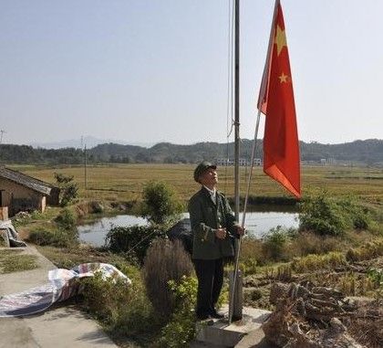 在家门前自建的旗台升旗，李纯希已坚持15年多。潘东晓 摄
