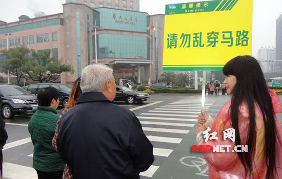 11月9日，株洲长江广场的十字路口的红路灯处出现了美女模特高举牌子指挥交通。 本报记者 周健 摄