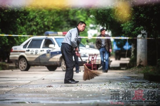 4月24日，浏阳古港镇，老镇长在清扫爆炸点附近的玻璃碎片。图/记者李坤