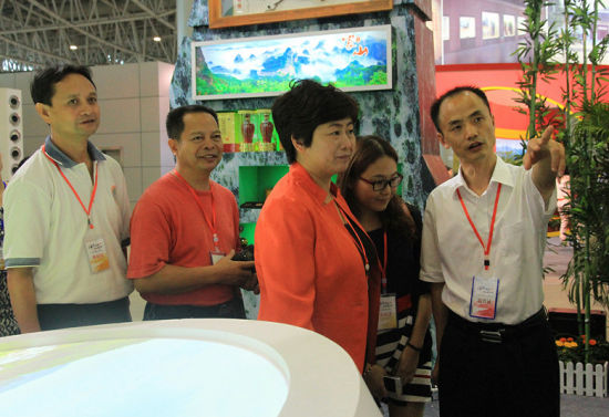 县委副书记陈秋良向邵阳市旅游局局长许红梅介绍崀山展馆的展销情况。