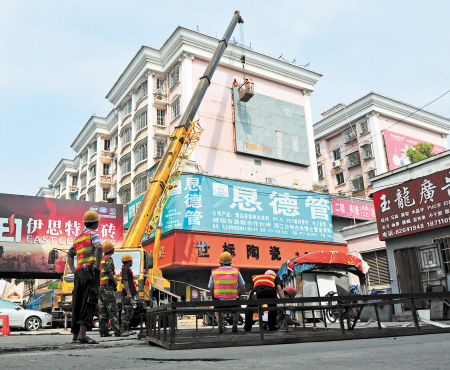 近日，在马王堆陶瓷城，芙蓉区城管工作人员正在对墙面上的两块巨型广告牌进行拆除。 邹麟 摄