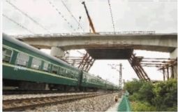 2013年6月24日，长沙县暮云镇，一列火车从在建的沪昆高铁桥下驶过。当天，沪昆高铁长昆湖南段控制性工程——跨京广铁路大桥全部完工。（资料图片）